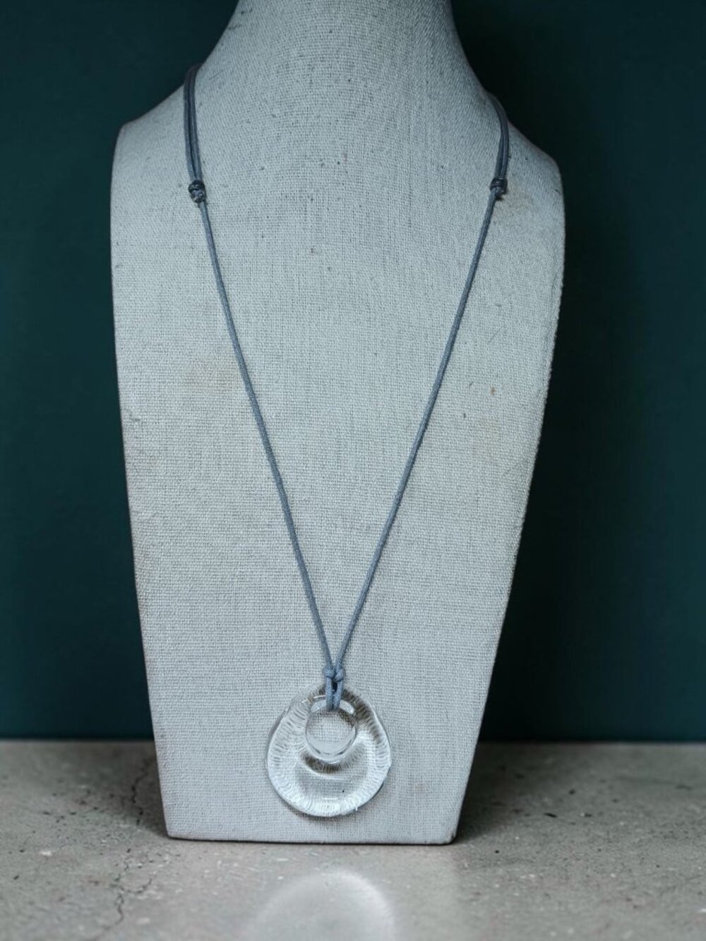 Clear Glass Oblong Circle Pendant on a Grey Cord